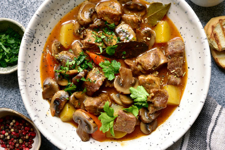 Meat stew ( beef bourguignon ) with vegetable and mushrooms in a white bowl over gray slate, stone or concrete background. Top view with copy space.の写真素材