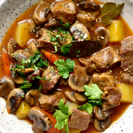 Meat stew ( beef bourguignon ) with vegetable and mushrooms in a white bowl over gray slate, stone or concrete background. Top view with copy space.の写真素材