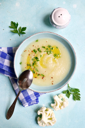 Cauliflower potato soup in a bowl over light blue slate, stone or concrete background . Top view with copy space.の写真素材