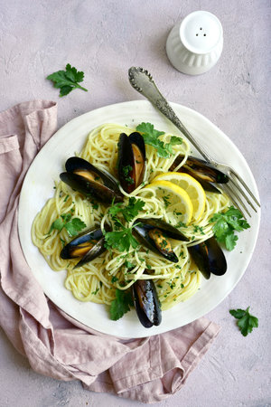 Delicious spaghetti with clams in a cream sauce on a white plate over light slate, stone or concrete background.Top view with copy space.の写真素材