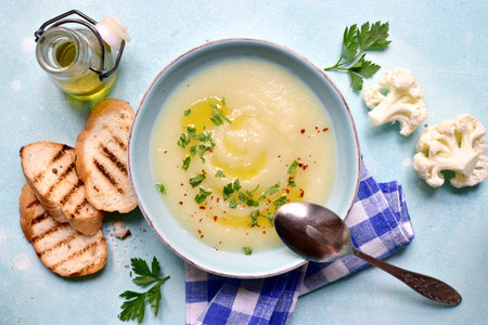 Cauliflower potato soup in a bowl over light blue slate, stone or concrete background . Top view with copy space.の写真素材