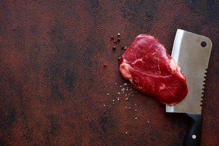 Raw organic rib eye steak with ingredients for making on a dark slate, stone or concrete background. Top view with copy space.の写真素材