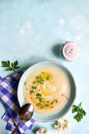 Cauliflower potato soup in a bowl over light blue slate, stone or concrete background . Top view with copy space.の写真素材