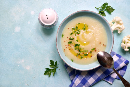 Cauliflower potato soup in a bowl over light blue slate, stone or concrete background . Top view with copy space.の写真素材