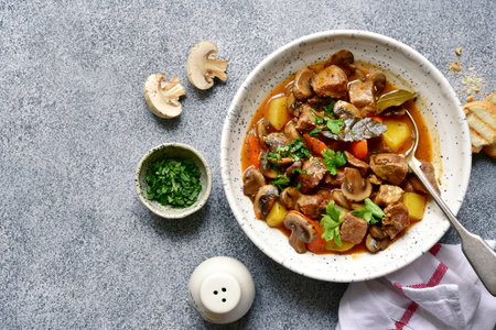 Meat stew ( beef bourguignon ) with vegetable and mushrooms in a white bowl over gray slate, stone or concrete background. Top view with copy space.の写真素材