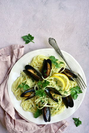 Delicious spaghetti with clams in a cream sauce on a white plate over light slate, stone or concrete background.Top view with copy space.の写真素材