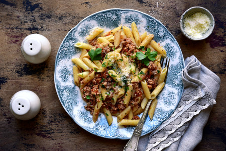 Traditional italian pasta bolognese on a plate over rustic wooden background. Top view with copy space.の写真素材