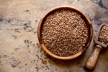 Raw organic buckwheat in a wooden bowl over rustic background. Top view with copy space.の写真素材