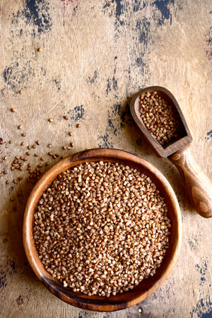 Raw organic buckwheat in a wooden bowl over rustic background. Top view with copy space.の写真素材