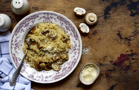 Risotto with mushrooms and cheese on a vintage plate over rustic wooden background. Top view with copy space.の写真素材