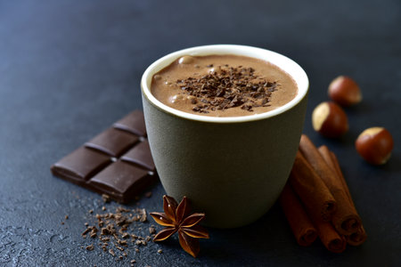 Spicy hot chocolate with ingredients for making on a black slate, stone or concrete background.の写真素材