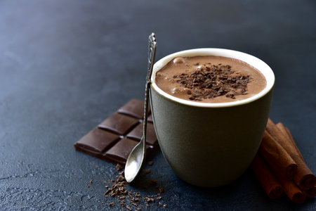 Spicy hot chocolate with ingredients for making on a black slate, stone or concrete background.の写真素材