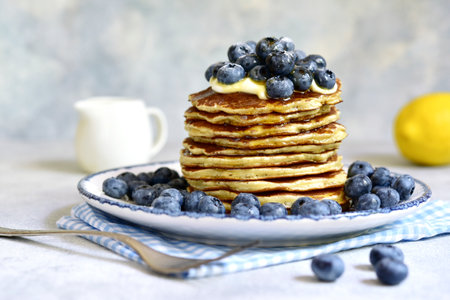 Lemon pancakes with fresh blueberry and whipped cream on a light backgroundの写真素材