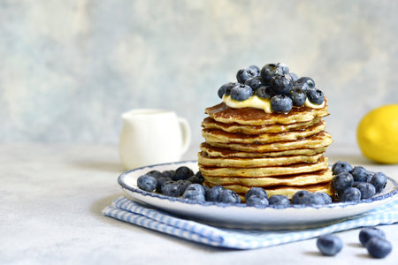Lemon pancakes with fresh blueberry and whipped cream on a light backgroundの写真素材