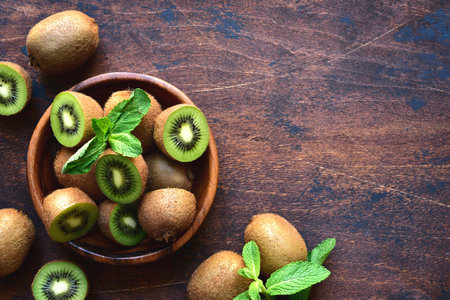 Fresh kiwi in a wooden bowl on a dark rustic background. top view with copyspace.の写真素材