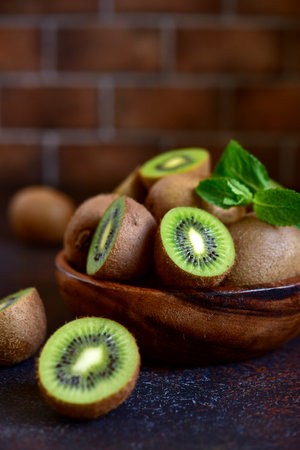 Fresh kiwi in a wooden bowl on a dark slate background.の写真素材