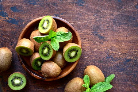 Fresh kiwi in a wooden bowl on a dark rustic background. top view with copyspace.の写真素材