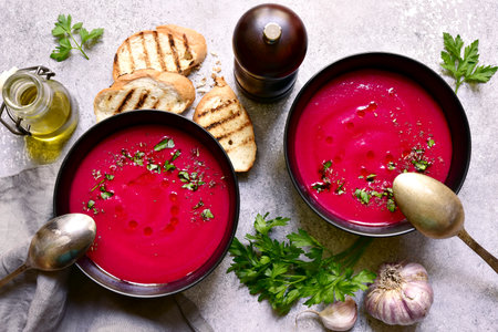 Delicious beetroot soup in a black bowls over light gray slate, stone or concrete background. Top view with copy space.の写真素材
