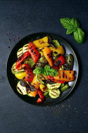 Grilled colorful vegetable: bell pepper, zucchini, eggplant on a black plate over dark slate, stone or concrete background. Top view with copy space.の写真素材