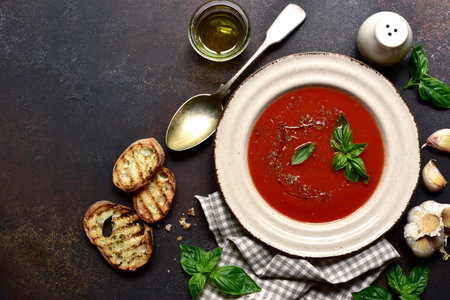 Spicy tomato soup or gazpacho on a dark slate, stone or concrete background. Top view with copy space.の写真素材