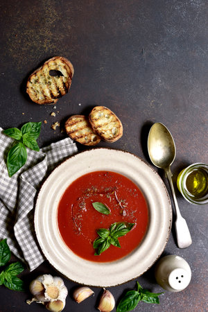 Spicy tomato soup or gazpacho on a dark slate, stone or concrete background. Top view with copy space.の写真素材