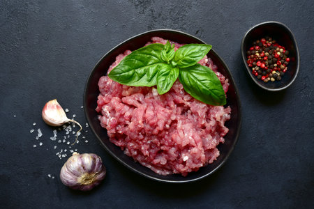 Homemade minced meat with spices on a black slate, stone or concrete background. Top view with copy space.の写真素材