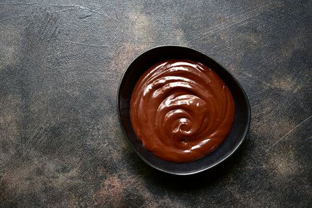 Homemade chocolate ganache in a blck bowl on a dark slate, stone or concrete background. Top view with copy space.の写真素材