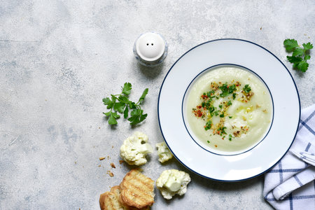 Thick cauliflower soup in a plate over light gray slate, stone or concrete background. Top view with copy space.の写真素材