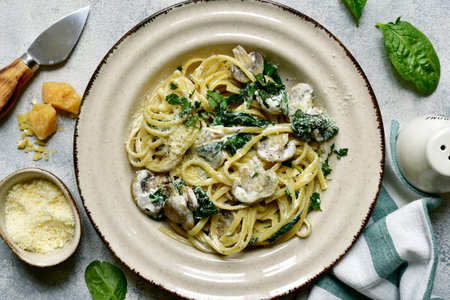 Pasta with spinach and mushrooms in a cream sauce on a light gray slate, stone or concrete background. Top view with copy space.の写真素材