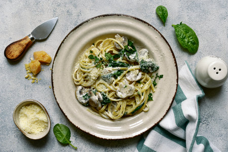 Pasta with spinach and mushrooms in a cream sauce on a light gray slate, stone or concrete background. Top view with copy space.の写真素材
