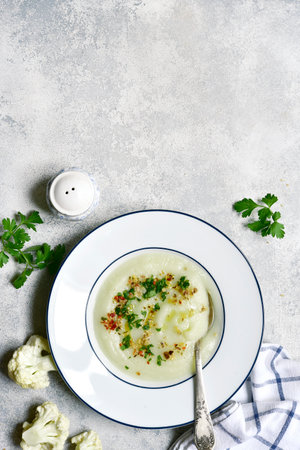 Thick cauliflower soup in a plate over light gray slate, stone or concrete background. Top view with copy space.の写真素材