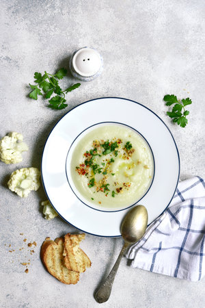 Thick cauliflower soup in a plate over light gray slate, stone or concrete background. Top view with copy space.の写真素材