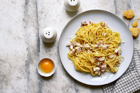 Spaghetti alla carbonara - traditional Italian pasta dish on a plate over light gray slate, stone or concrete background. Top view with copy space.の写真素材