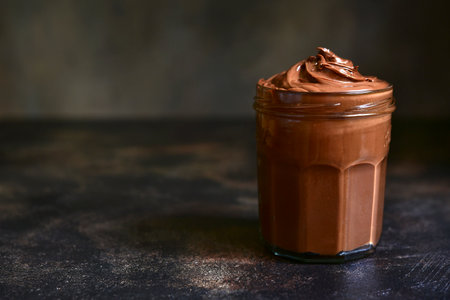 Homemade delicious chocolate and nut spread in a jar on a dark slate, stone or concrete background.の写真素材