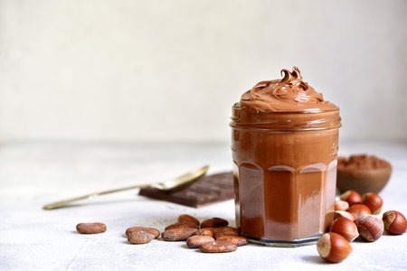 Homemade delicious chocolate and nut spread in a jar on a white slate, stone or concrete background.の写真素材