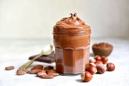 Homemade delicious chocolate and nut spread in a jar on a white slate, stone or concrete background.の写真素材