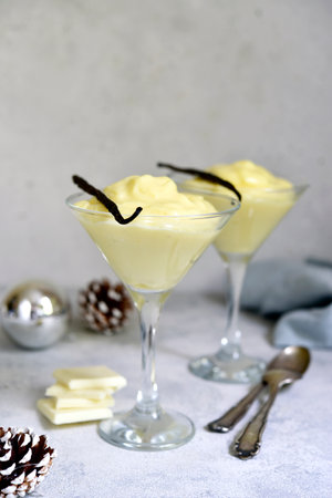 Festive delicious vanilla pudding with white chocolate in a glasses on light slate, stone or concrete background.の写真素材