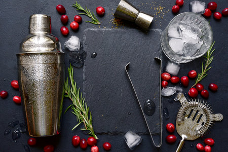Ingredients and props for making festive Christmas cocktail with cranberries and rosemary on a black slate, stone or concrete background. Top view with copy space.の写真素材