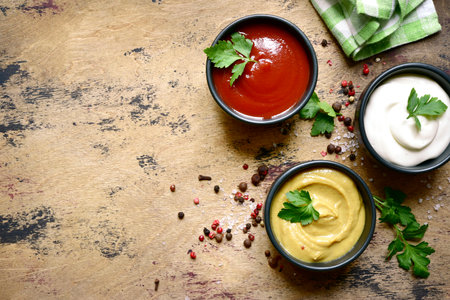 Set of popular sauces in a black bowls on a wooden slate, stone or concrete background. Top view with copy space.の写真素材