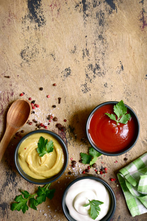 Set of popular sauces in a black bowls on a wooden slate, stone or concrete background. Top view with copy space.の写真素材