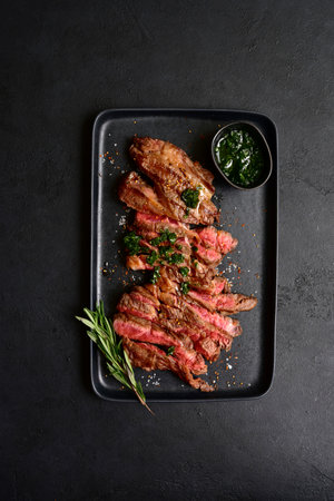 Grilled marbled beef steak on a black plate over dark slate, stone or concrete background. Top view with copy space.の写真素材