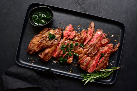 Grilled marbled beef steak on a black plate over dark slate, stone or concrete background. Top view with copy space.の写真素材