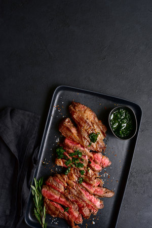 Grilled marbled beef steak on a black plate over dark slate, stone or concrete background. Top view with copy space.の写真素材