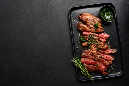 Grilled marbled beef steak on a black plate over dark slate, stone or concrete background. Top view with copy space.の写真素材