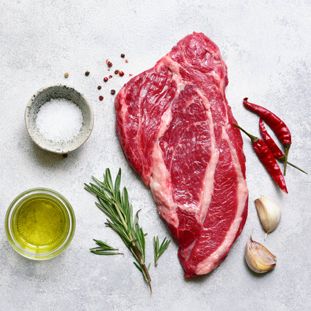 Raw organic marbled beef steak with ingredients for cooking on a light gray slate, stone or concrete background. Top view with copy space.の写真素材