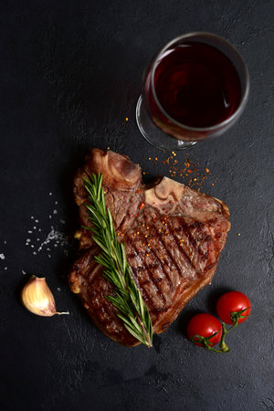 Grilled T-bone beef steak on a dark slate, stone or concrete background. Top view with copy space.の写真素材