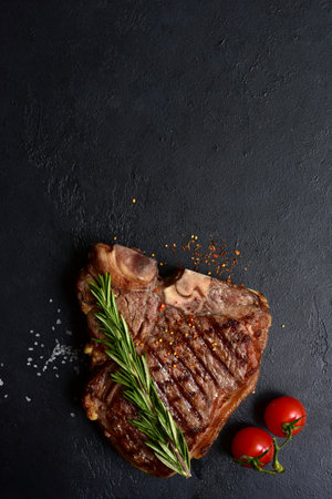 Grilled T-bone beef steak on a dark slate, stone or concrete background. Top view with copy space.の写真素材