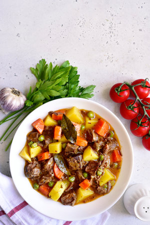 Meat stew with vegetables on a white slate, stone or concrete background. Top view with copy space.の写真素材