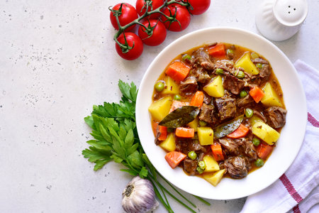 Meat stew with vegetables on a white slate, stone or concrete background. Top view with copy space.の写真素材