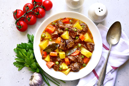 Meat stew with vegetables on a white slate, stone or concrete background. Top view with copy space.の写真素材